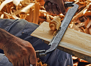 Hands using tool to shave wood