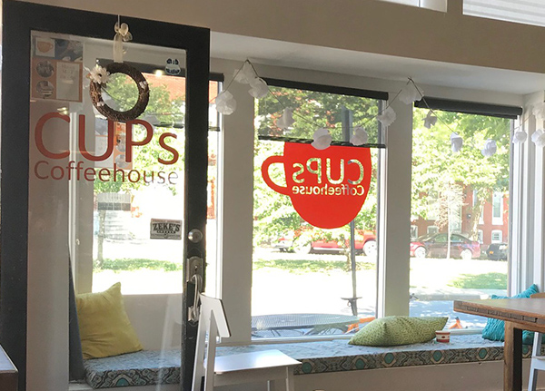 Windows with a decal on the window that says Cups Coffeehouse