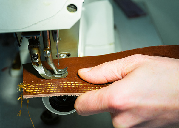 Person sews leather strap