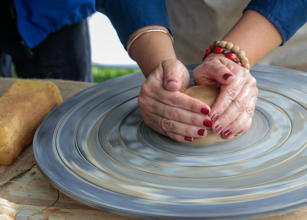 Hands shaping clay on pottery wheel