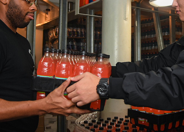 Person hands over a case of soda to another person