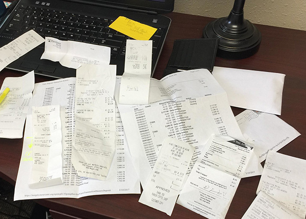 Paper receipts scattered on laptop keyboard and desk