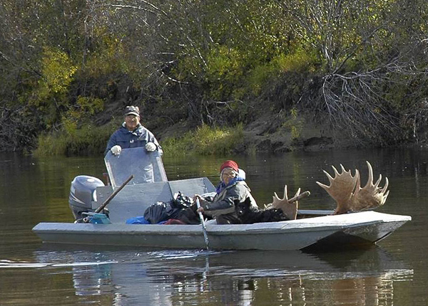 Man and woman in a boat with moose antlers sticking out of the boat