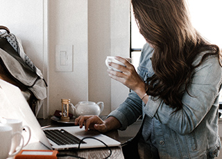 Woman drinking coffee and looking at a laptop