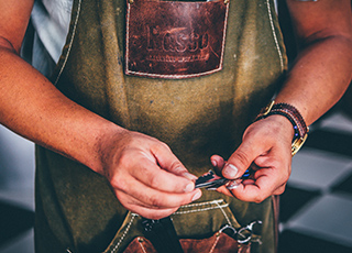 Person wearing apron with small craft item in their hands