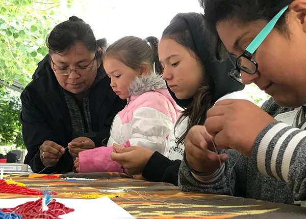 Woman showing children how to sew