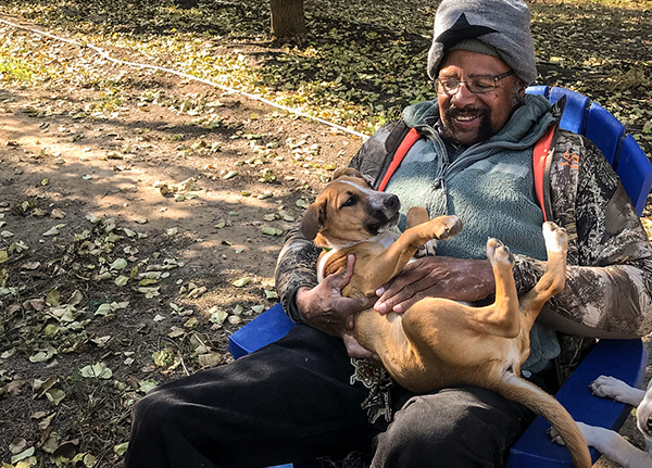 Man sitting in chair petting his dog