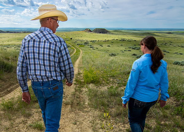 Man and woman walk down dirt road in a field