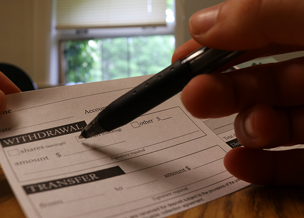 Person fills out withdrawal slip from the bank