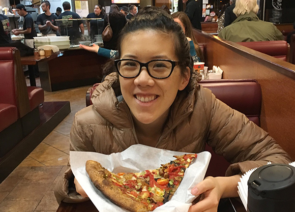 Young girl smiles with a piece of pizza