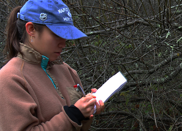 Young woman writes in a small notebook