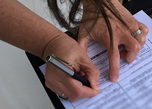 Person holding pen while filling out paperwork