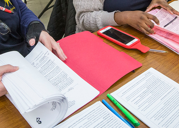 Two women at table flipping through paperwork