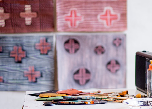 Art supplies with paintings hung in the background