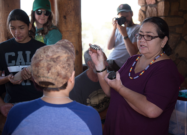 Woman holding up painted rocks and talking to a small crowd