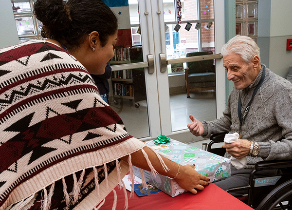 Woman hands older gentleman a wrapped gift