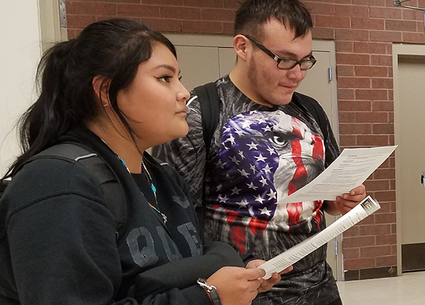 Two people hold paper handouts