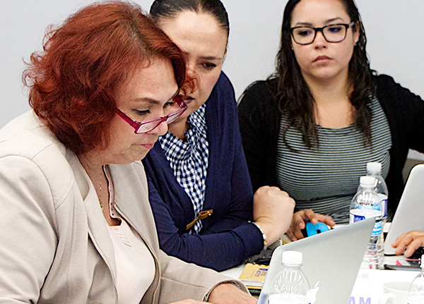 Three women look at a computer screen