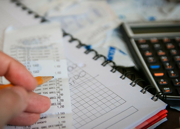 Person holding pencil going through long paper receipt