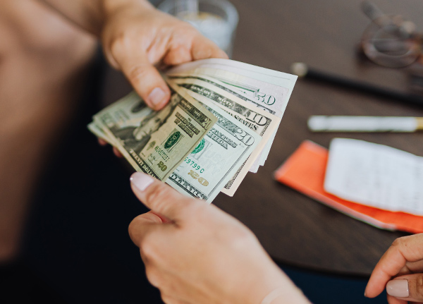 Person handing another person a stack of cash